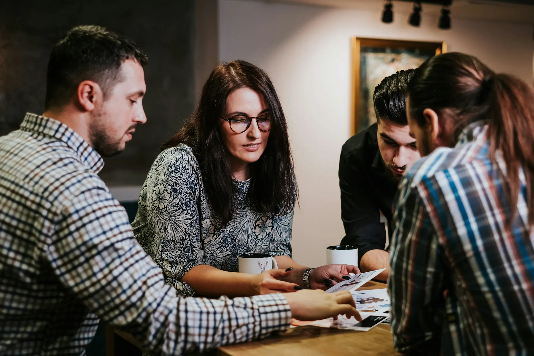 Quatre personnes relisent des documents autour d’une table