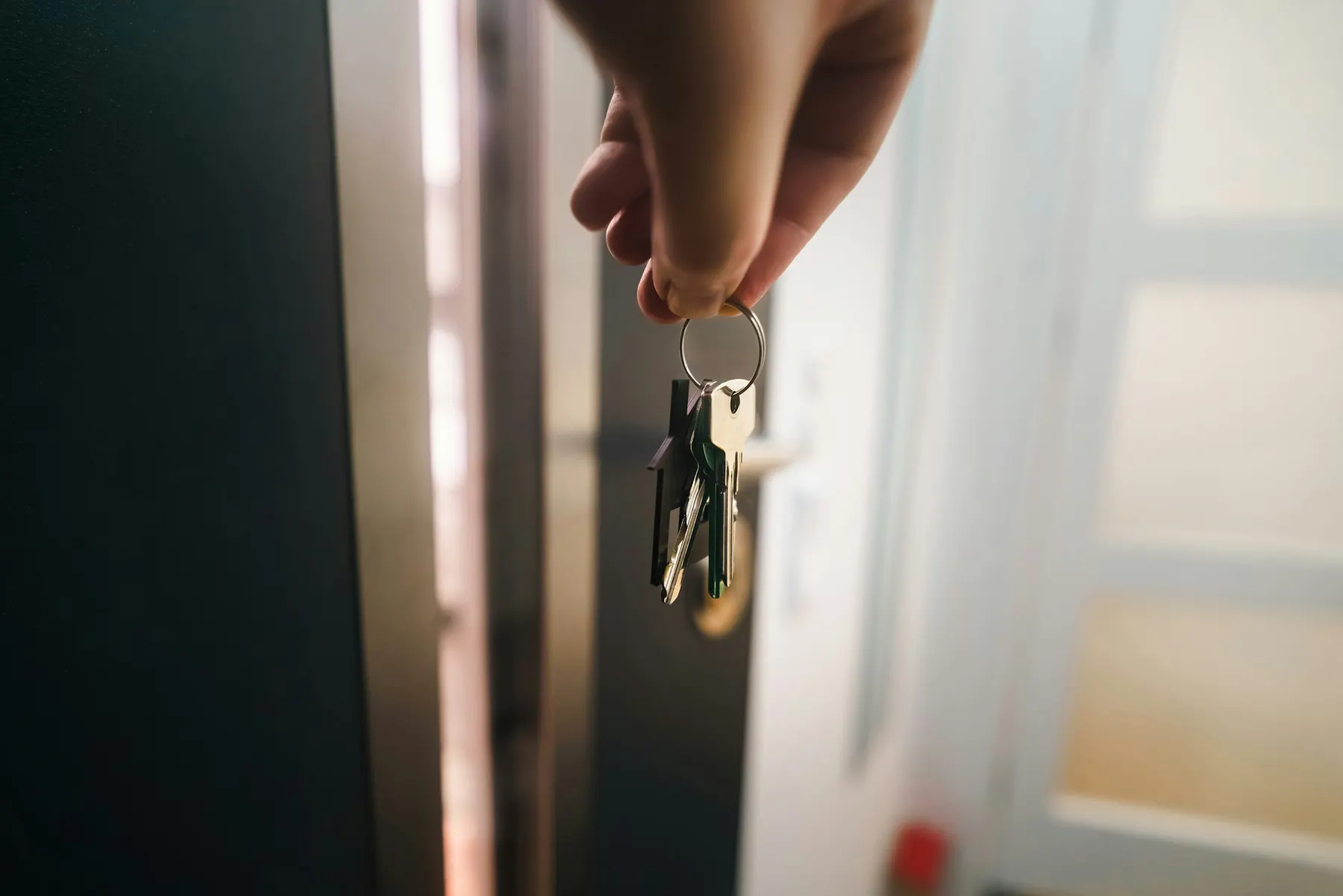 Une main tourne une clé dans la serrure d’une porte