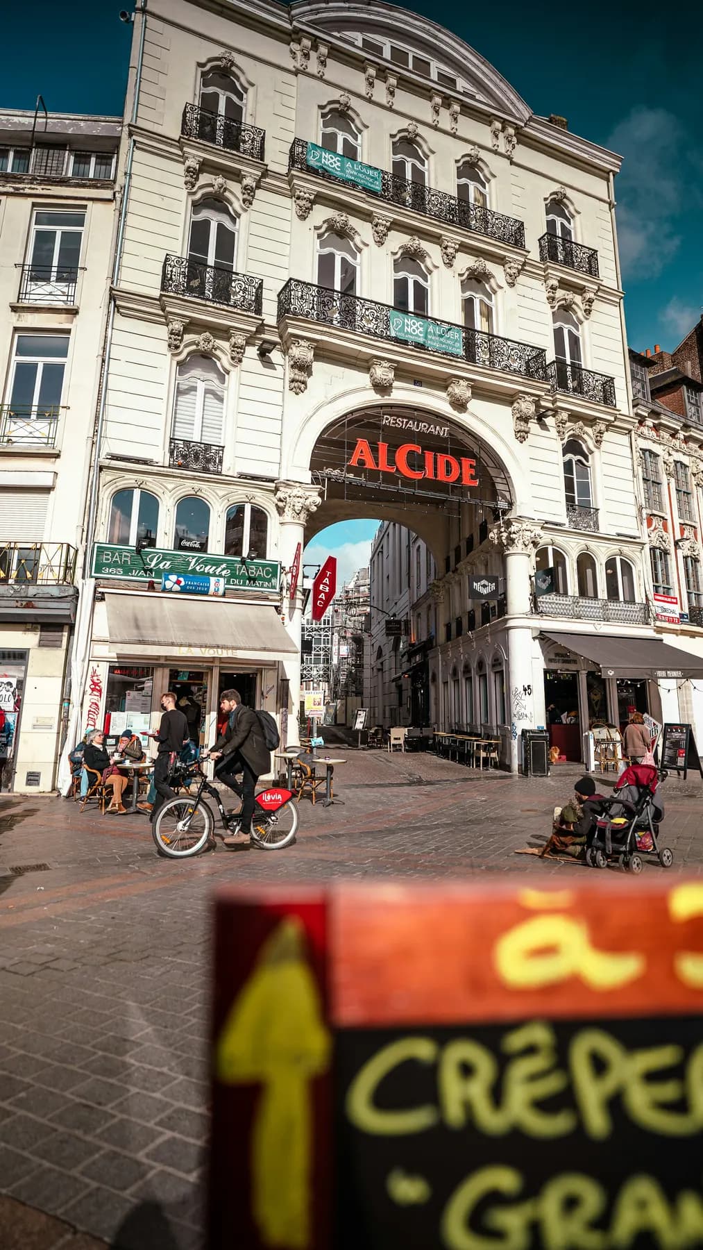 Une rue commerçante du centre de Lille, des cyclistes devant les terrasses