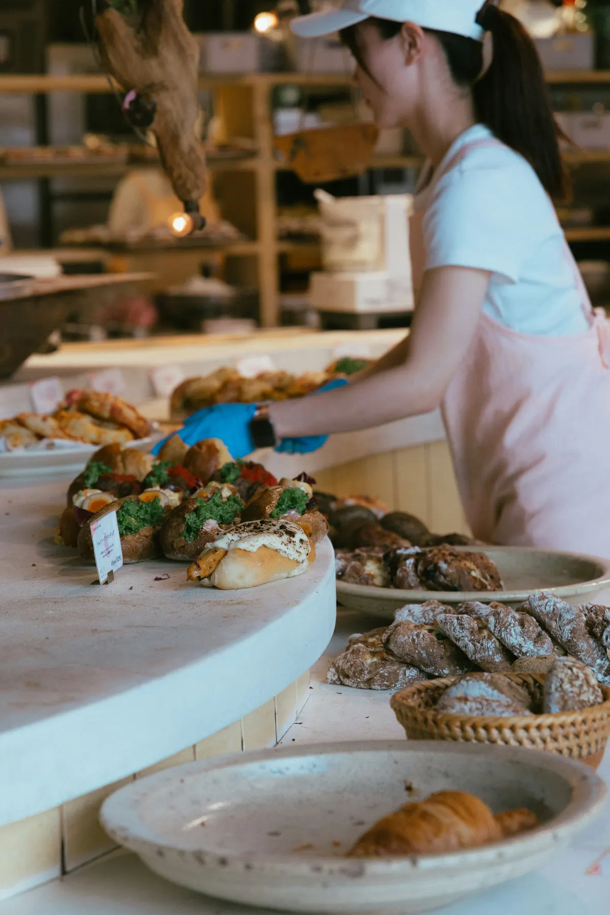 Une commerçante gantée dispose des pâtisseries sur son comptoir