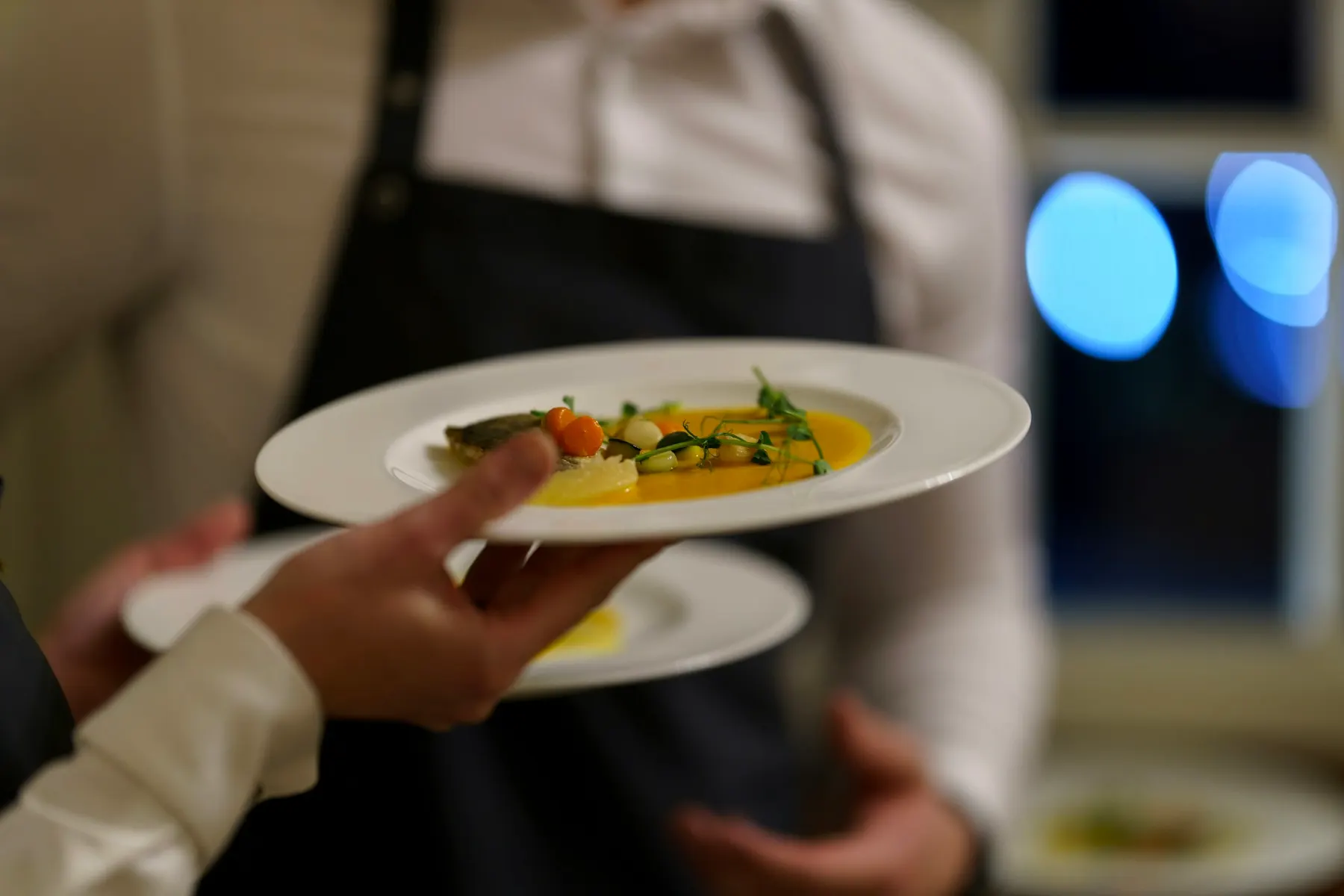 Un serveur porte deux assiettes dressées vers la salle